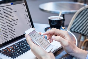 Business person reading emails on smartphone and laptop computer screen