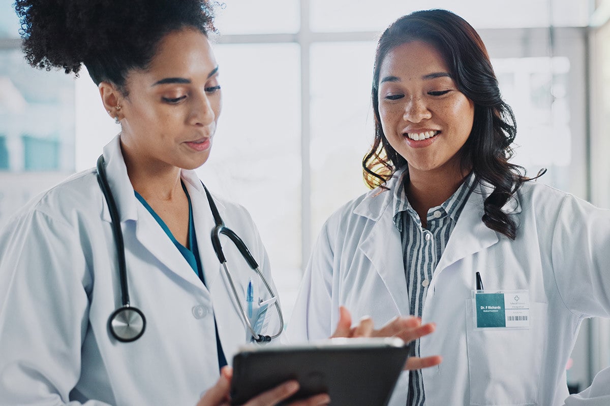 two doctors smiling while looking at a tablet